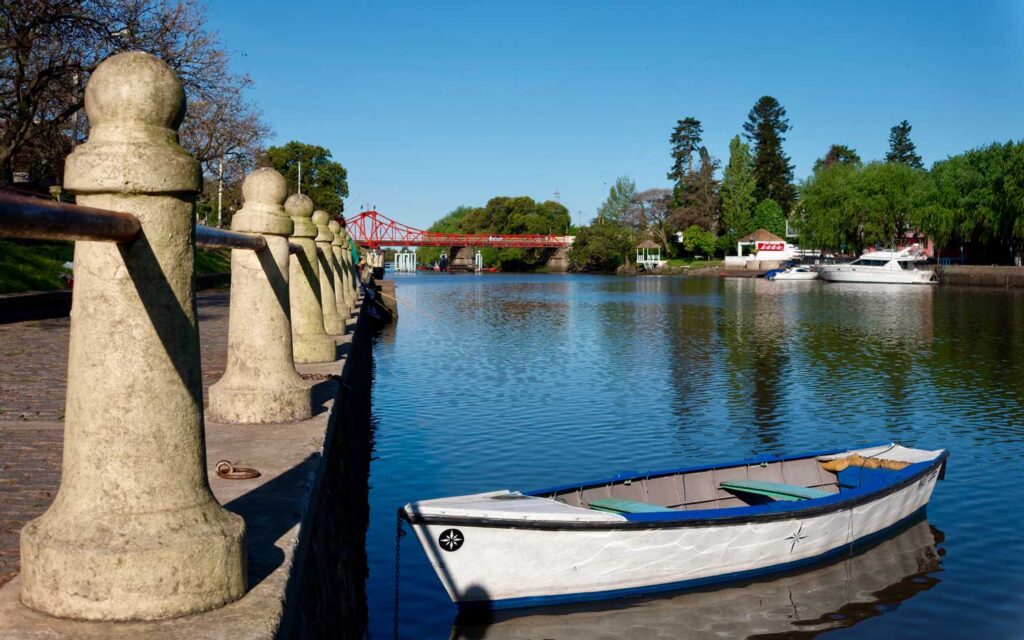 Flussufer in Carmelo Uruguay mit einem Boot und der roten Eisenbrücke