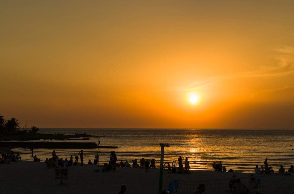 Ein atemberaubender Sonnenuntergang über dem Ramires Beach mit Badegästen, die einen Sommertag in Montevideo genießen