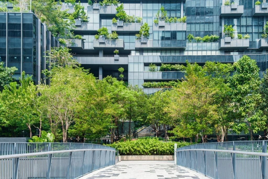 A modern building with green plants growing on its balconies and roof.