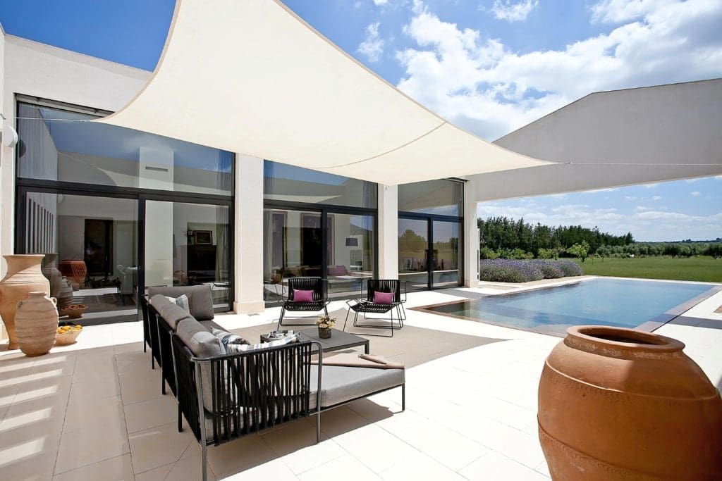 Modern patio with outdoor furniture and swimming pool next to a house