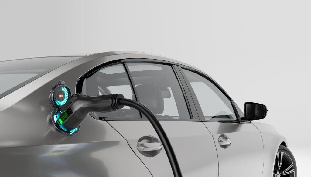A silver electric car being charged, with the charging cable connected and a digital display showing the battery charge level at 56%.